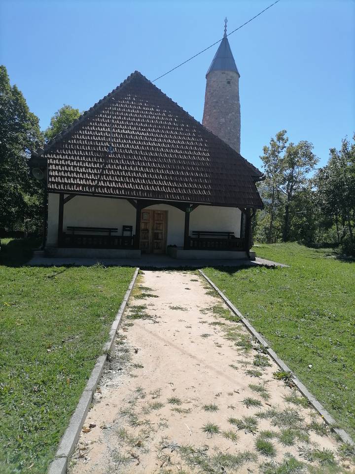 Una casa pequeña con bancos en el porche y césped.
