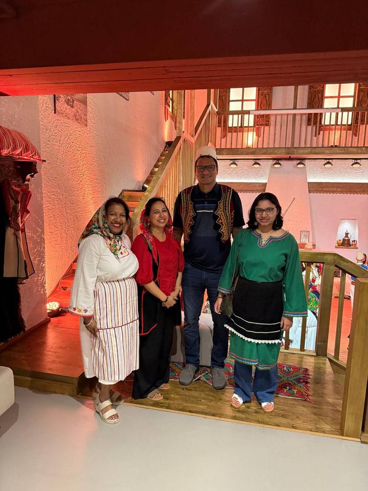 Groupe de personnes en tenue traditionnelle posant à l'intérieur.