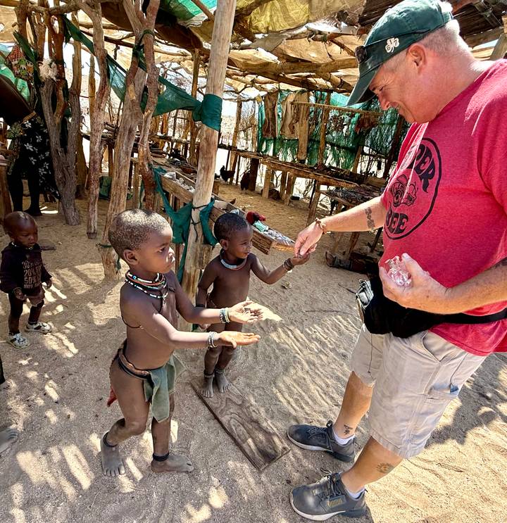 Personne interagissant avec des enfants dans un cadre rural.