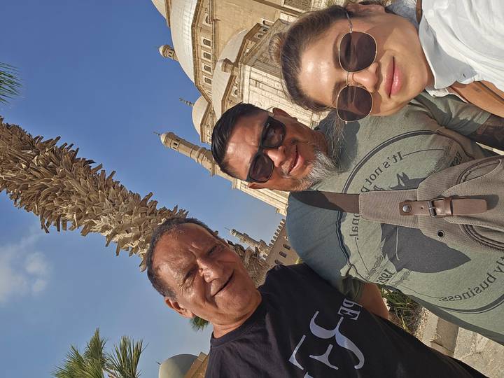 Drie mensen die een selfie nemen met een moskee op de achtergrond.