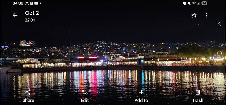 Paysage urbain de Kusadasi la nuit avec des reflets sur l'eau.
