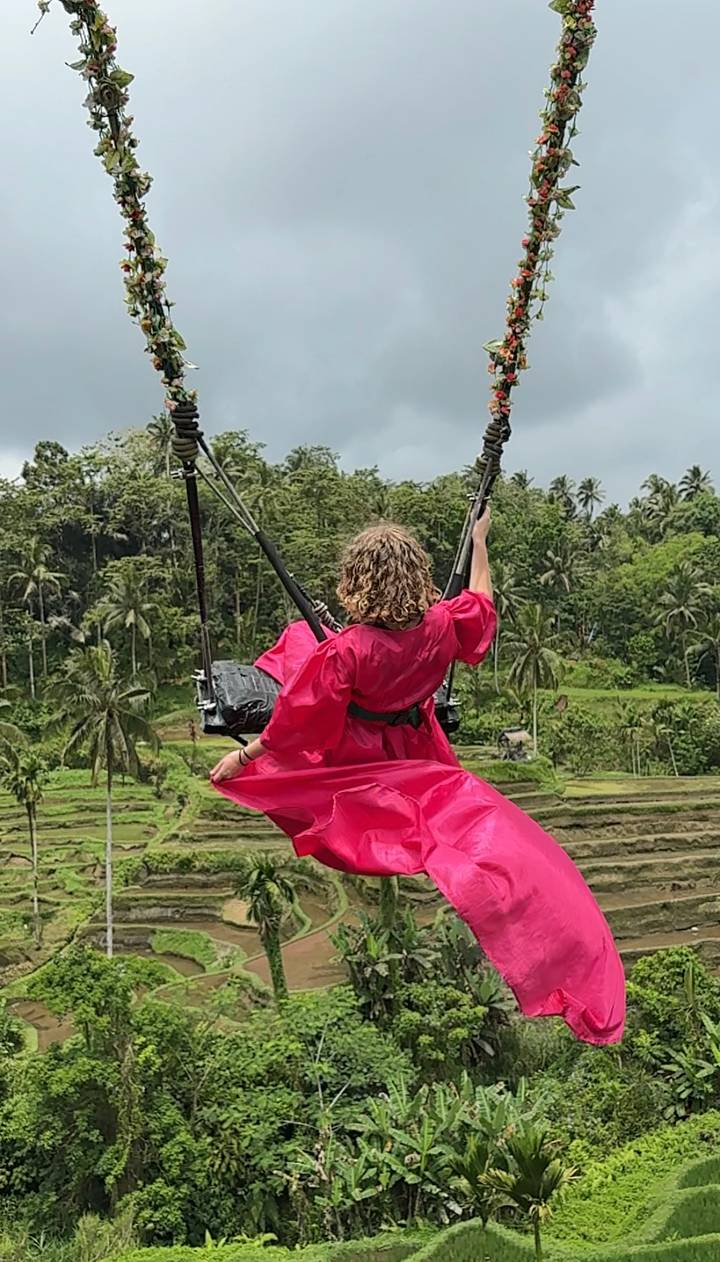Personne sur une balançoire avec une végétation luxuriante en arrière-plan.