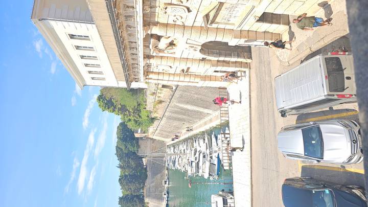 Vista histórica de la ciudad con barcos amarrados a lo largo del agua y edificios de piedra.