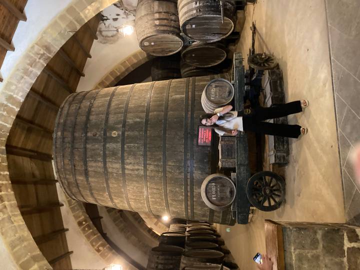 Personne debout à côté d'un grand tonneau en bois.