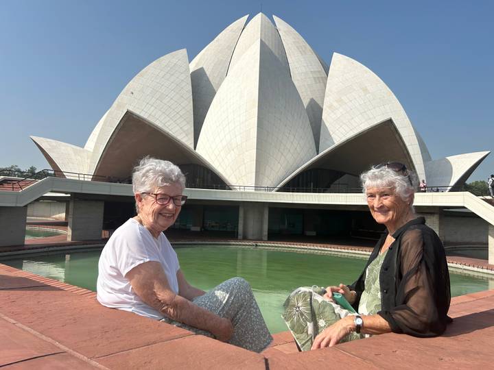 Femmes assises devant le Temple du Lotus, souriantes.