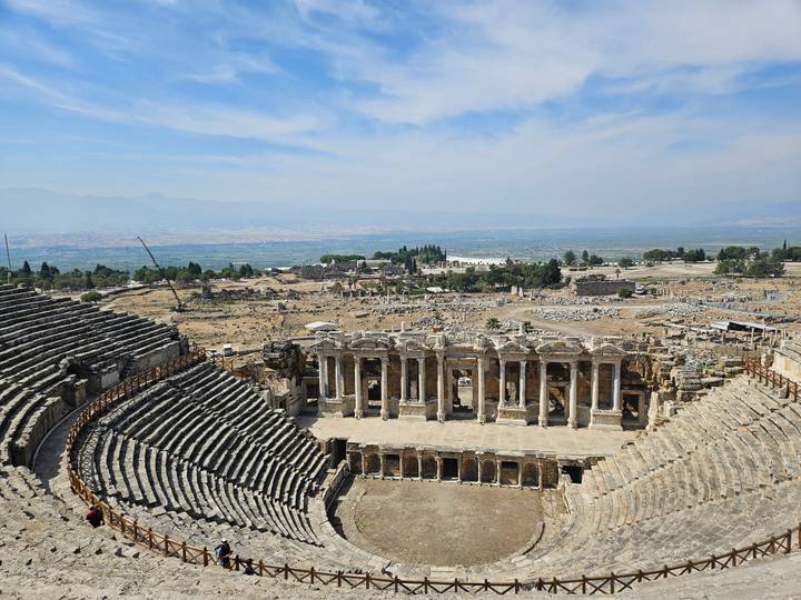 Amphithéâtre antique surplombant un vaste paysage.