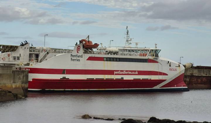 Ferry amarré à un port avec un logo visible.