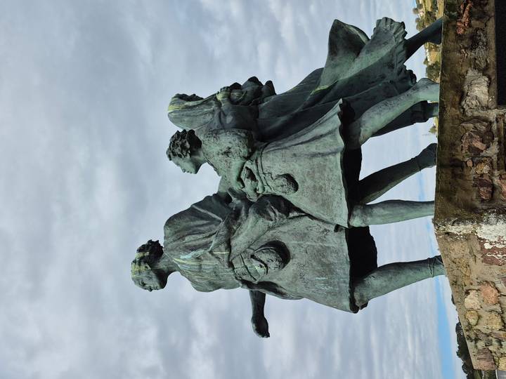 Statue de pierre de trois figures regardant au loin.