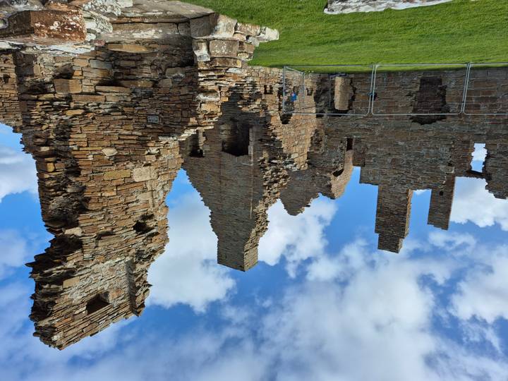 Ruines d'un ancien château de pierre sous un ciel bleu.