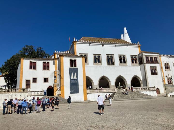 Group of tourists outside a historic white building.