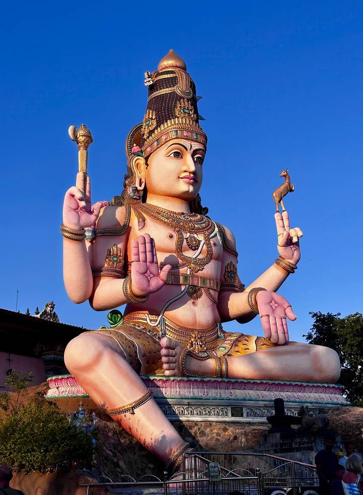 Statue colorée d'une divinité contre un ciel bleu clair.