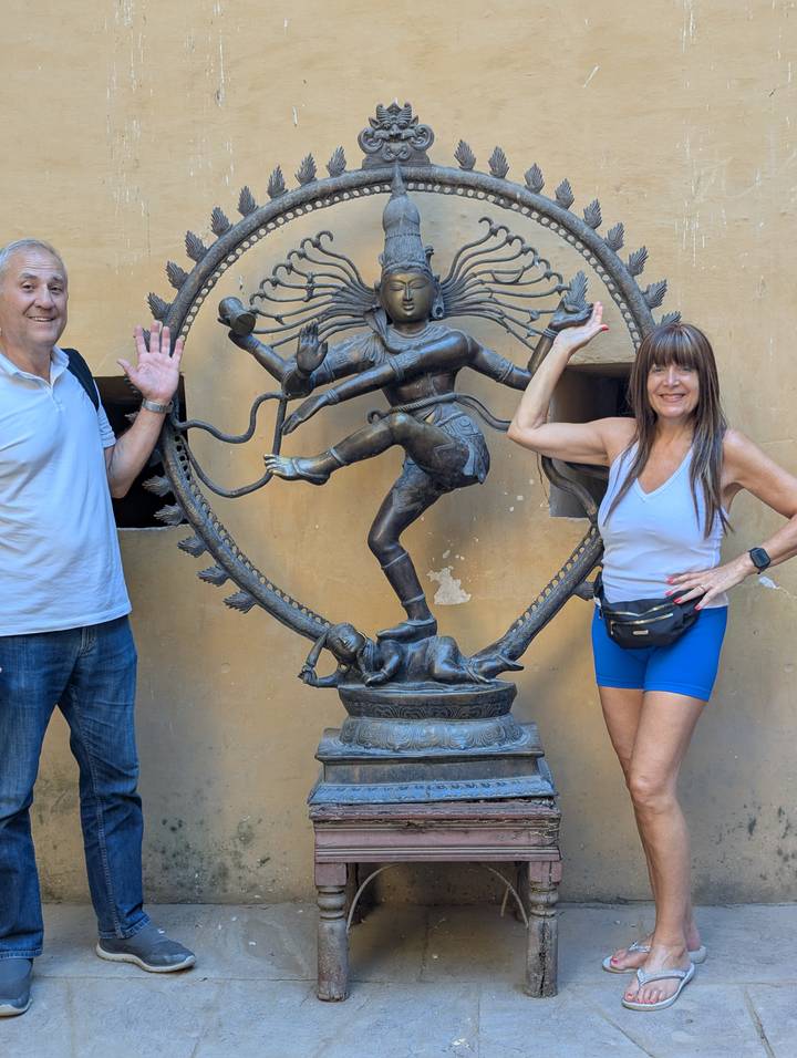 Statue of Shiva with two people posing beside it.