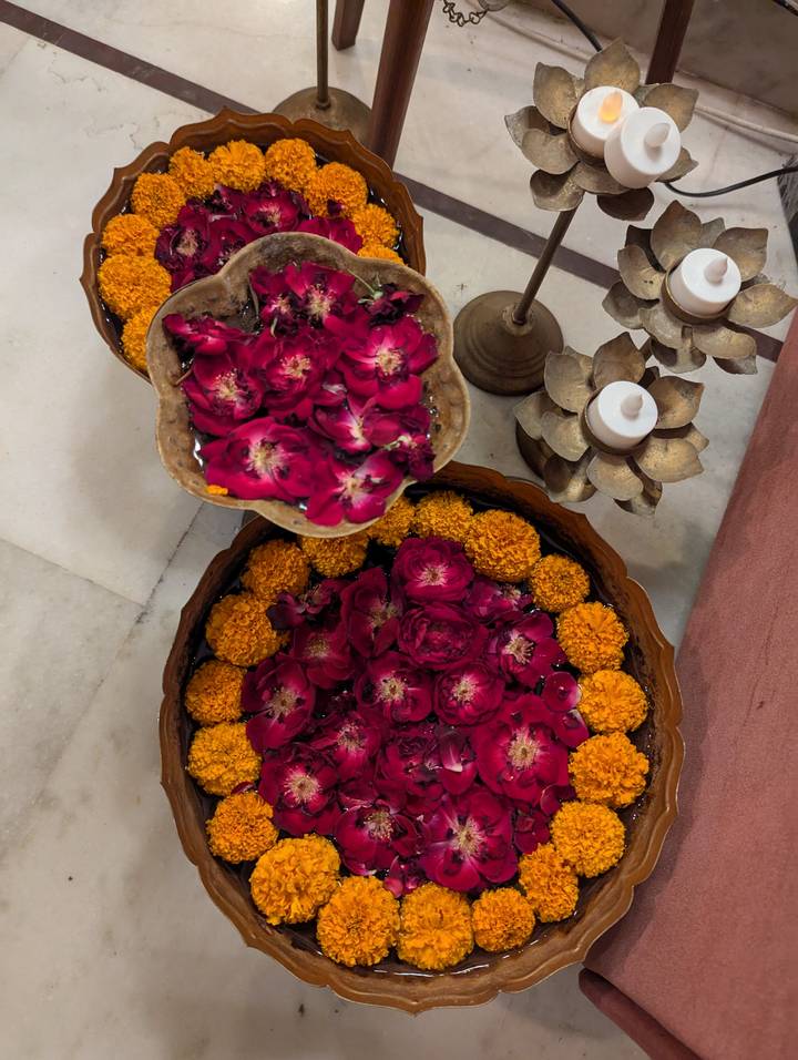 Bowls of floating flowers and candles, viewed from above.