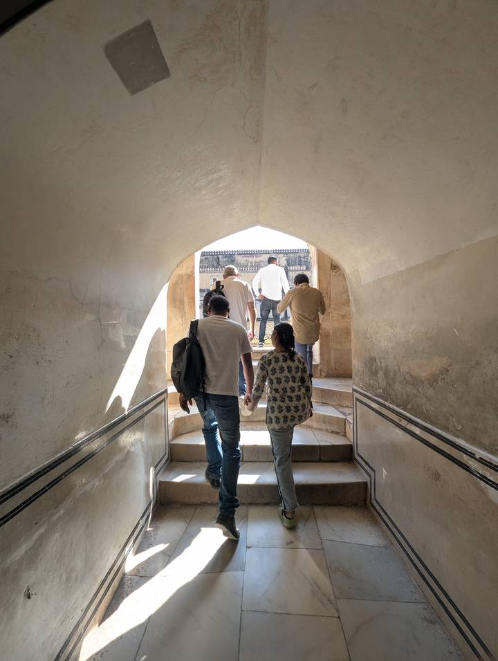 A group of people walking through a historic archway with light streaming in.