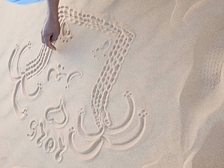 Motifs arabes dessinés dans le sable avec un doigt.