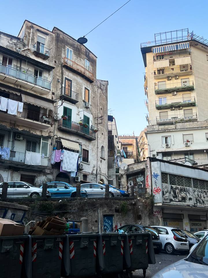 Scène de rue urbaine avec bâtiments résidentiels, balcons et vêtements qui sèchent dehors.