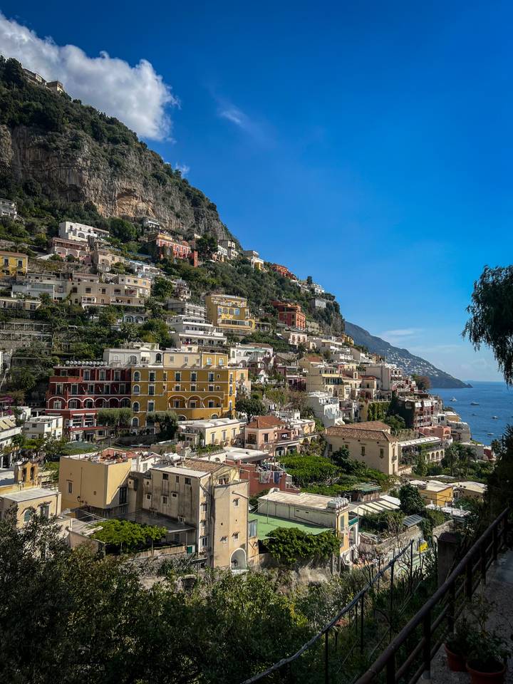 Ville colorée à flanc de colline avec des maisons serrées les unes contre les autres, surplombant la mer.