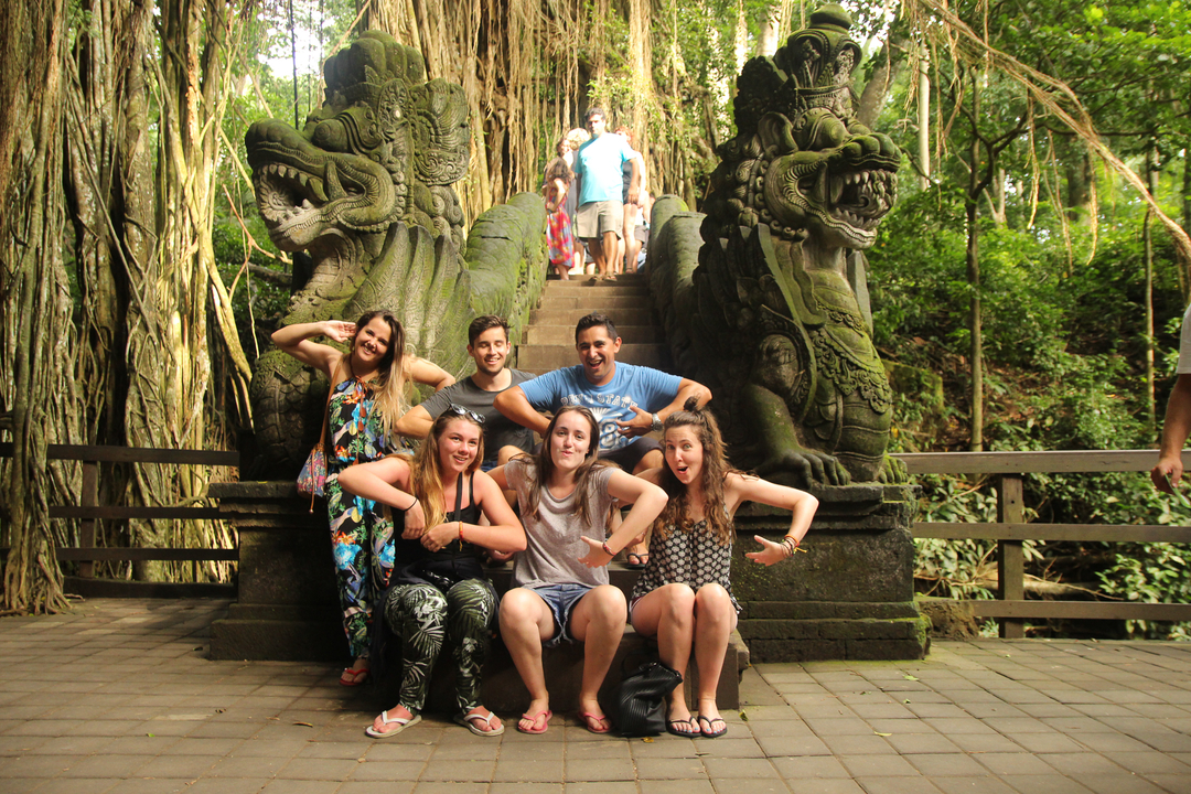 Group posing at stone steps flanked by carved animal statues.