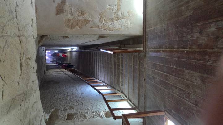 People walking down a narrow ancient corridor.