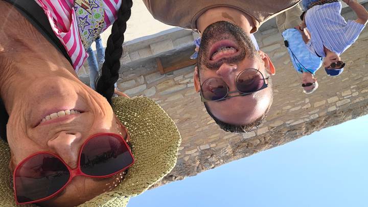 Selfie of two people smiling with a stone wall background.