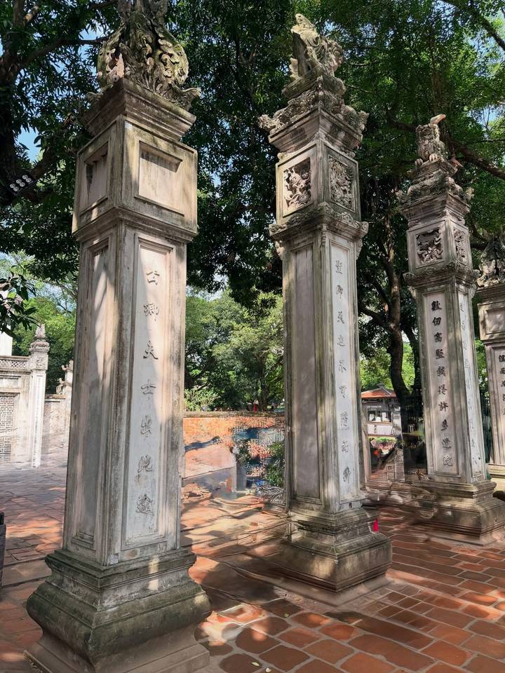 Piliers de pierre gravés de textes dans un cadre de jardin.