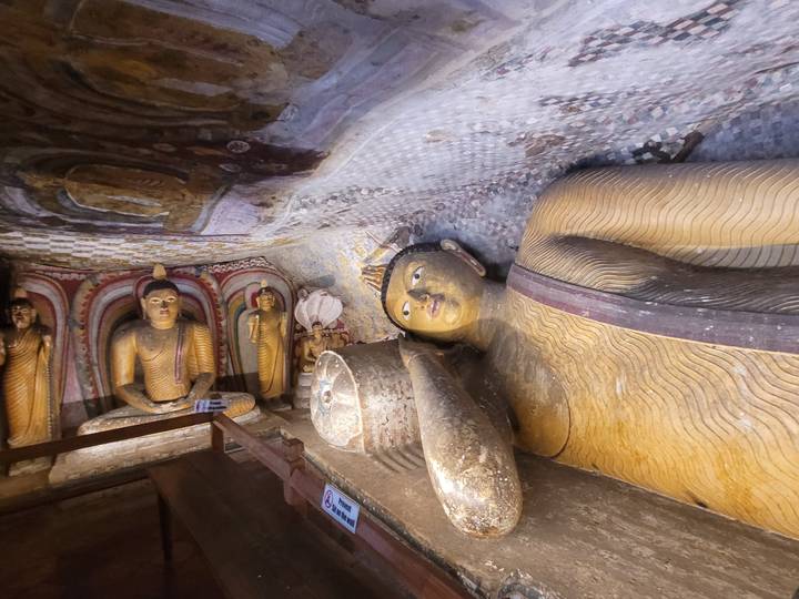 Statues de Bouddhas allongés et assis dans une grotte.