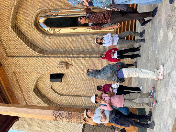 Turistas escuchando a un guía fuera de un edificio histórico con intrincados trabajos de ladrillo.