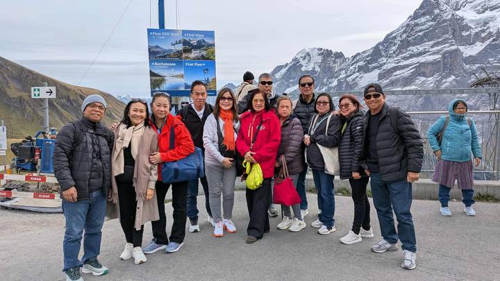 Groupe de personnes debout avec une vue sur des montagnes enneigées.