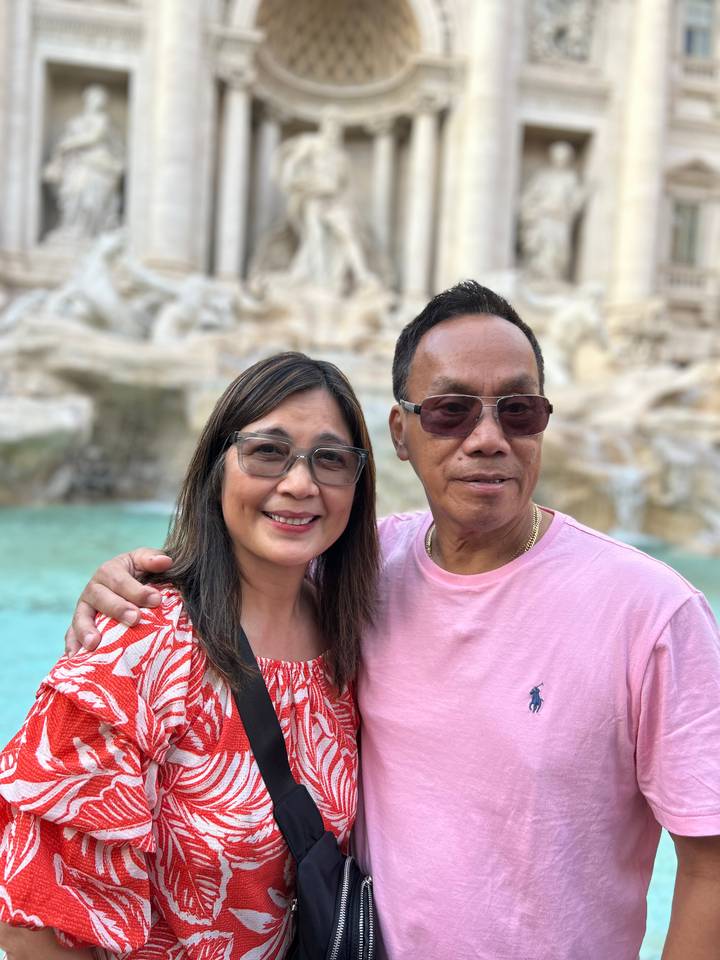 Couple souriant avec de l'eau turquoise en arrière-plan.