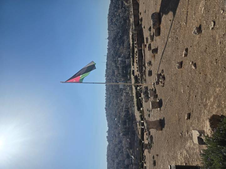 Panoramic view of a flagpole with a cityscape in the background.