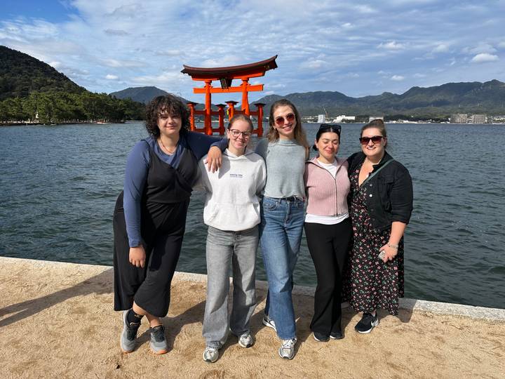 Grupo de personas posando frente a la puerta torii flotante del Santuario Itsukushima.