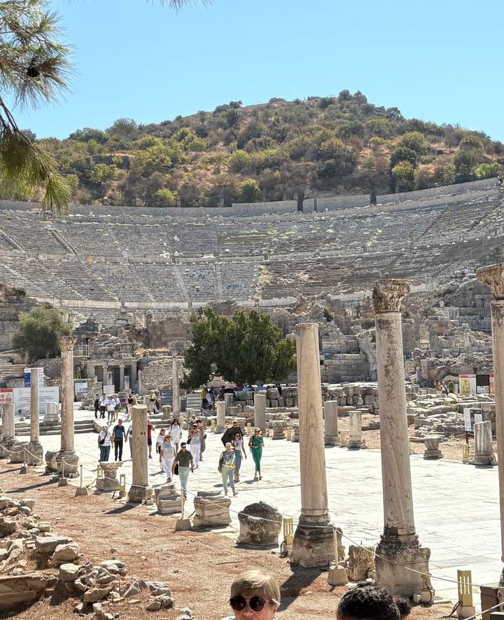 Amphithéâtre antique avec des touristes explorant les ruines.
