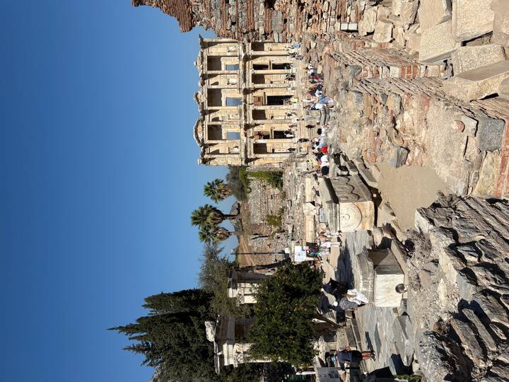 Touristes visitant les ruines antiques avec des colonnes et des structures historiques.