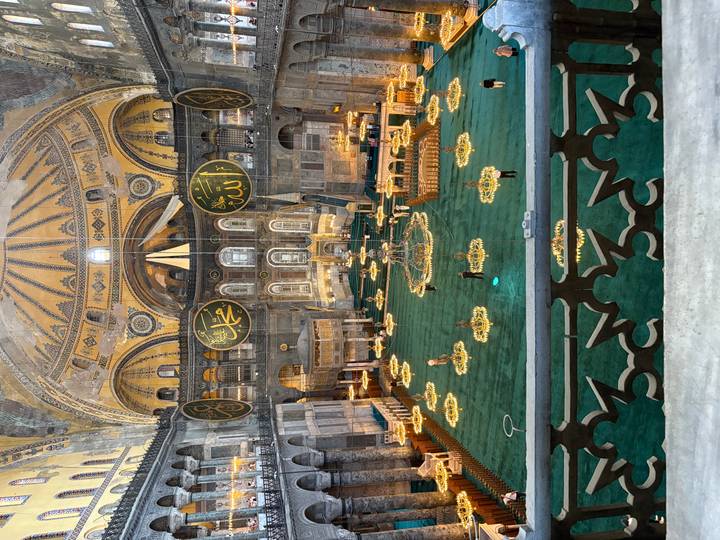 Vue intérieure d'une grande mosquée avec des décorations ornées et des lustres.