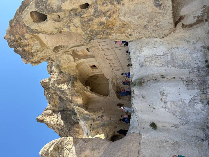 Touristes explorant une architecture ancienne taillée dans la roche dans une région montagneuse.