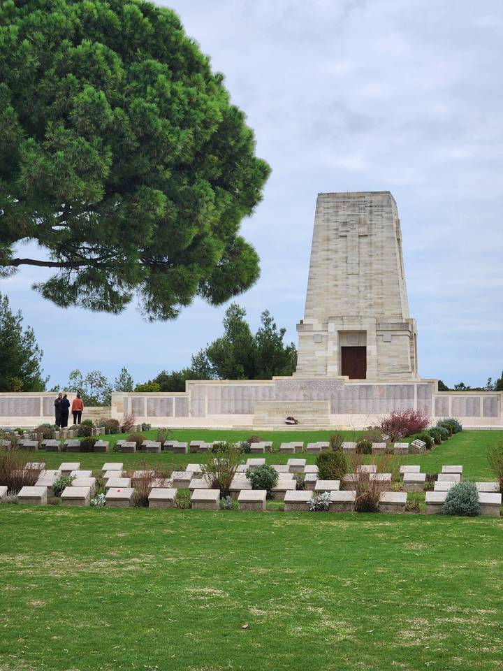 Monument commémoratif entouré d'arbres avec des personnes en visite.