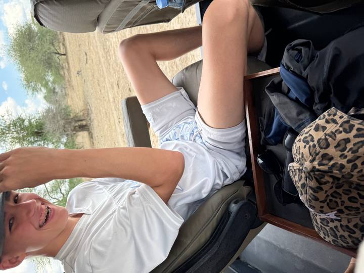 Person, die in einem Safari-Jeep sitzt und Freizeitkleidung trägt.