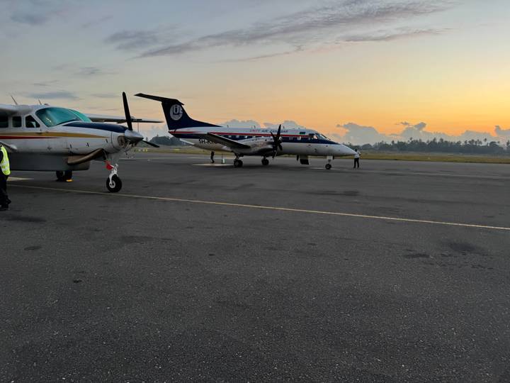 Flugzeuge geparkt auf einem Rollfeld bei Sonnenuntergang.