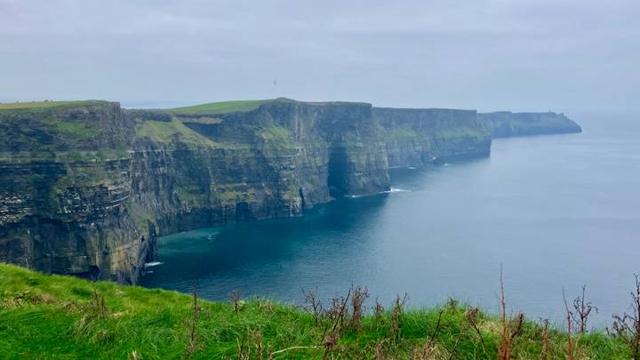 Malerische Aussicht auf die Cliffs of Moher mit Meer und bewölktem Himmel.
