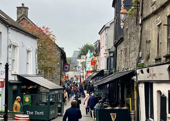Belebte Straßenszene in einer historischen Stadt mit vielen Fußgängern.