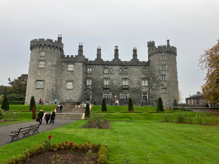 Kilkenny Castle mit Menschen, die im Vordergrund spazieren gehen.