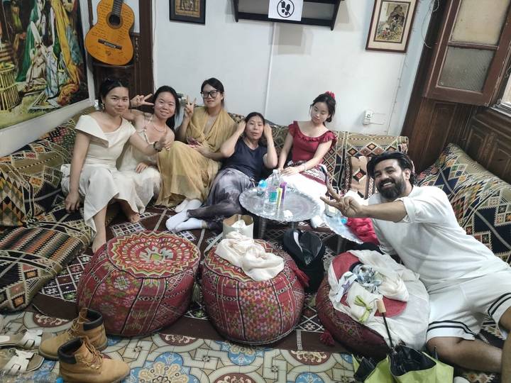 Groupe de personnes assises sur des coussins à motifs à l'intérieur.