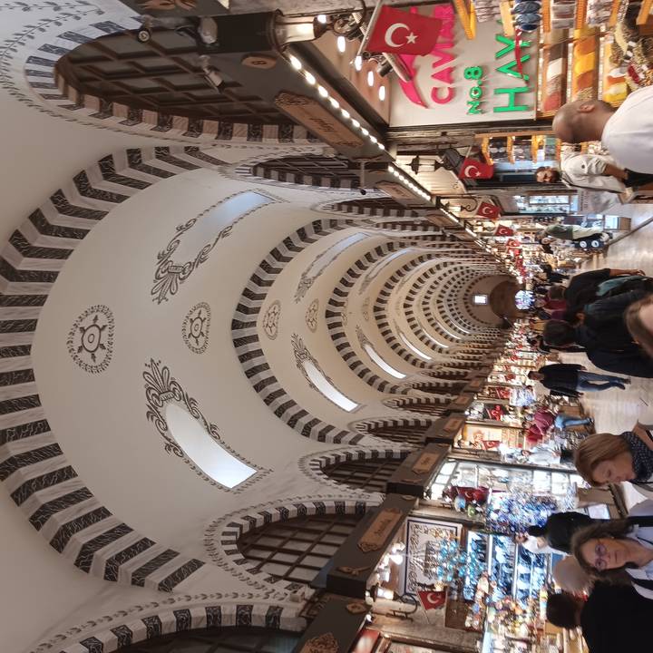 Des gens faisant leurs courses dans un grand marché intérieur avec des arches décoratives.