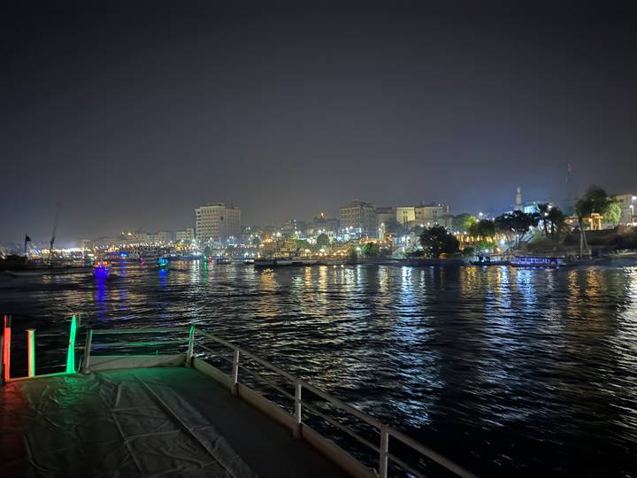 Vue nocturne d'un front de mer urbain avec des bâtiments illuminés.