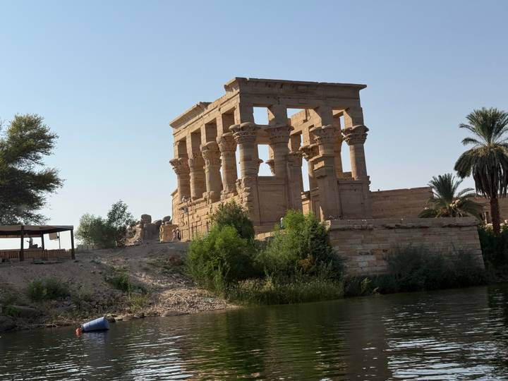 Temple égyptien antique avec des colonnes le long d'une berge.