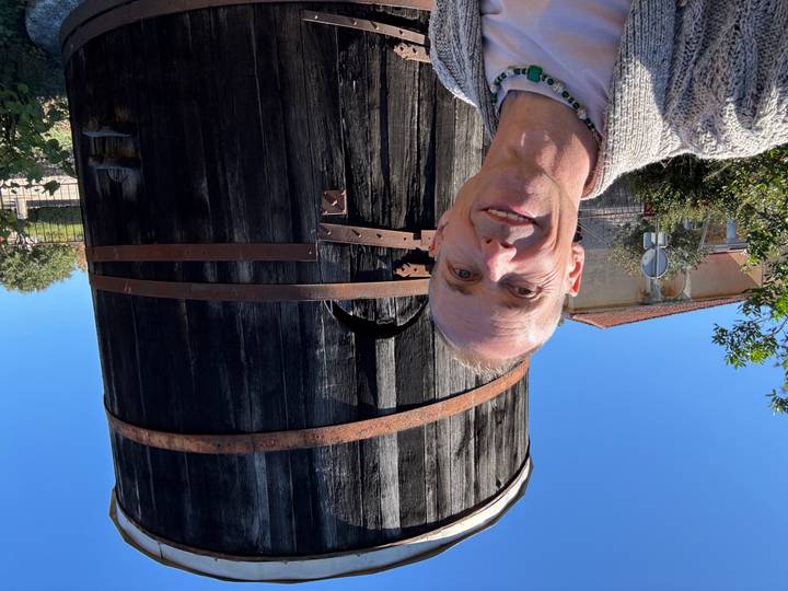 Gros plan d'une personne avec un grand tonneau en bois en arrière-plan.