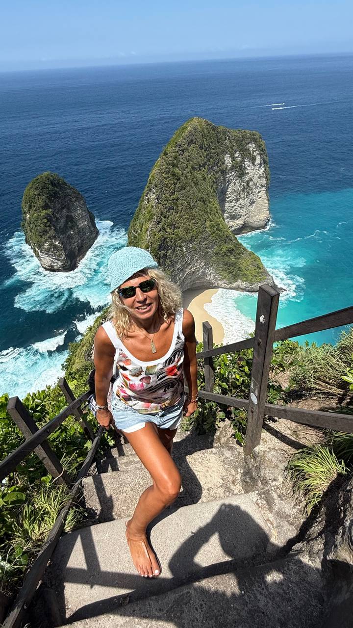 Femme posant sur un escalier surplombant des falaises et l'océan.