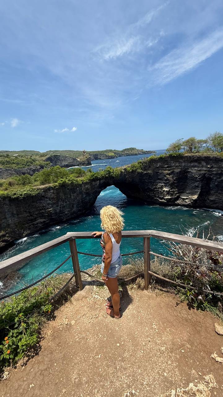 Femme regardant une arche naturelle au-dessus de l'eau.