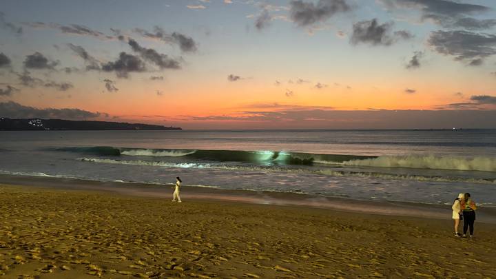 Des gens qui marchent sur une plage au coucher du soleil.