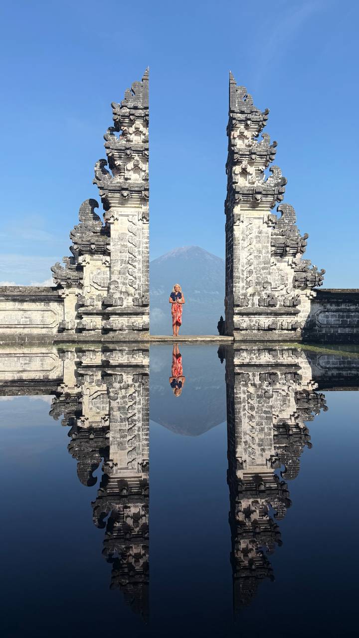 Femme debout devant un portail se reflétant sur l'eau.